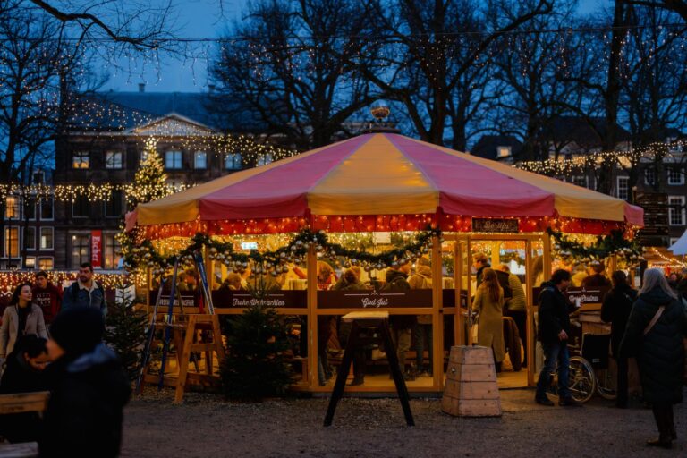 Verlichte kraam met bezoekers op de Royal Christmas Fair aan het Lange Voorhout in Den Haag