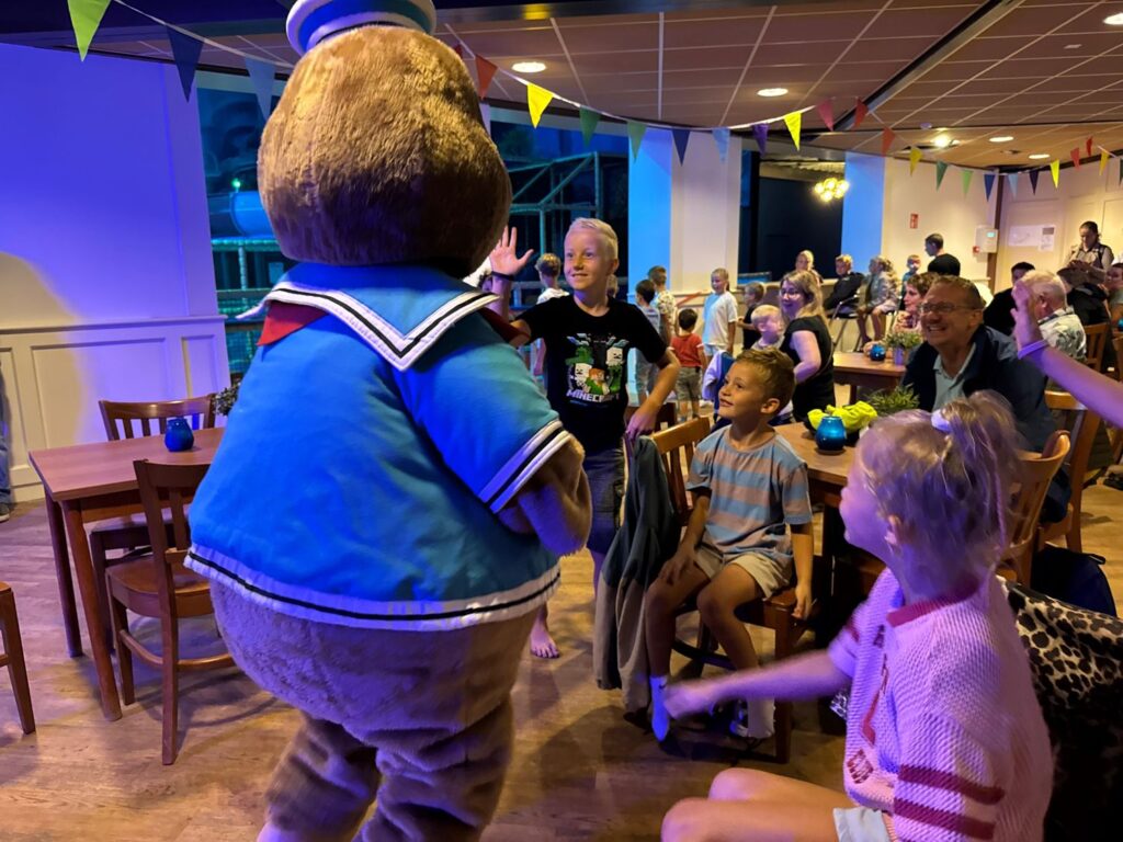 Kinderen zwaaien naar de mascotte tijdens de opening