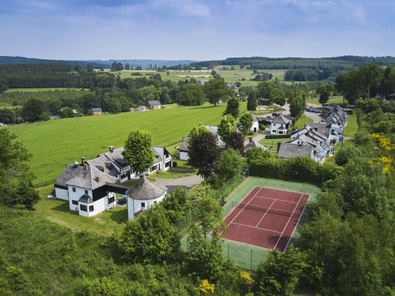 Luchtfoto van Landal Village les Cottales met vakwerkhuizen en tennisbaan in de Ardennen