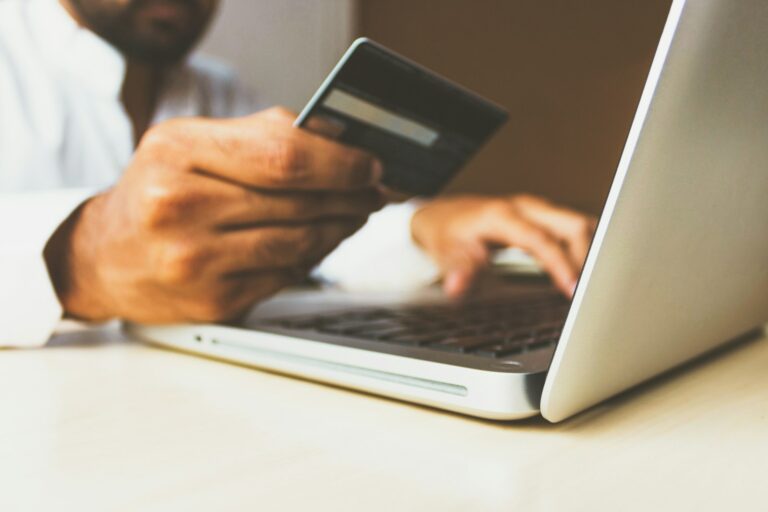 Iemand boekt online en houdt een betaalpas bij een laptop