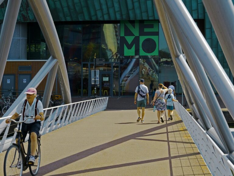 Fietser en bezoekers op de brug naar NEMO in Amsterdam