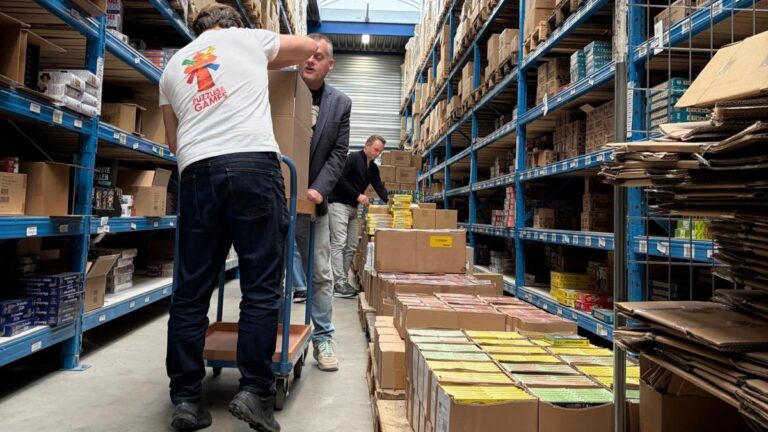 Directeuren van spellenbedrijven vullen karren met spellen in een magazijn voor de Nationale Spellenweek